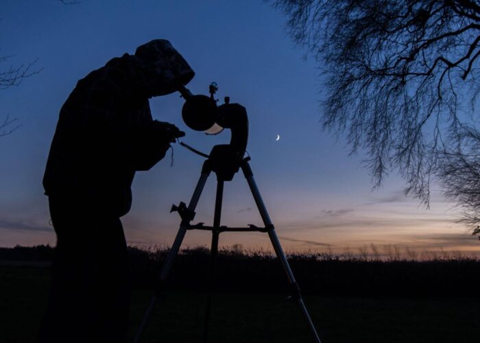 Man looking at the moon through telescope