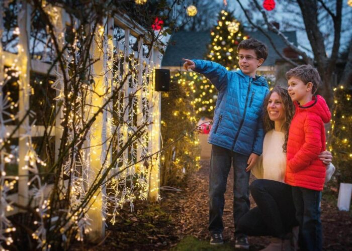a mother with a boy and girl infront of Christmas lights