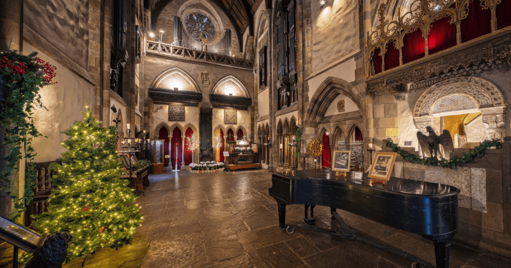 A Christmas tree and other holiday decorations in the medieval gothic-inspired Great Hall within Hammond Castle Museum