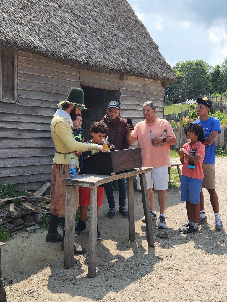 A family gathered around learning at the Plimoth Patuxet Museum