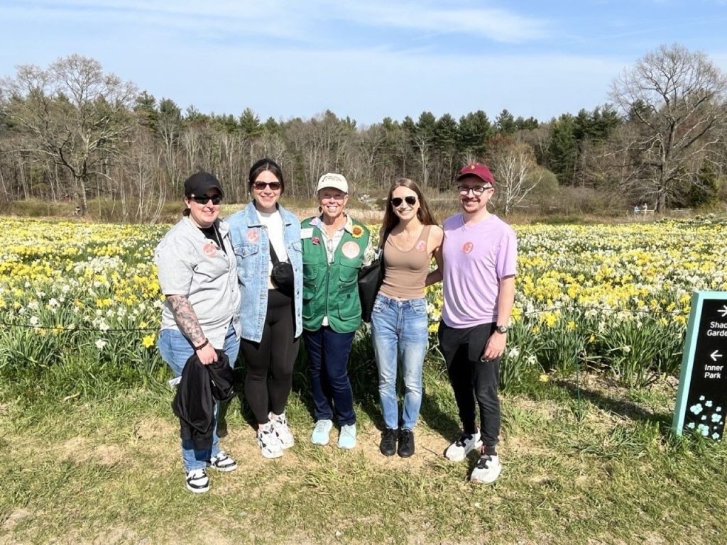 Group of tourists at the New England Botanic Gardens smiling with a gardens volunteer