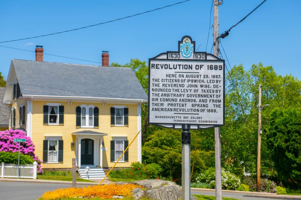 historic sign with a colonial house in the background in Ipswich, MA
